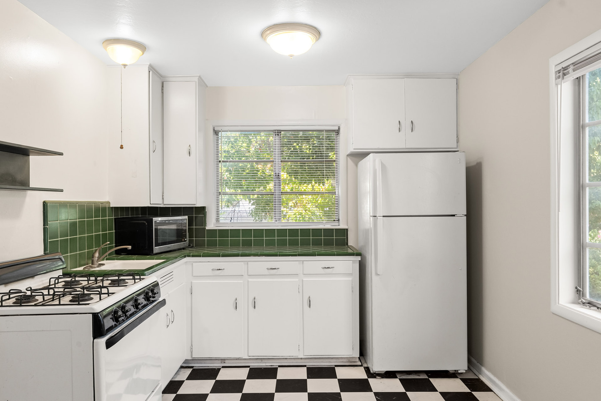 Unit kitchen with green tile counters, gas range, and full-size refrigerator