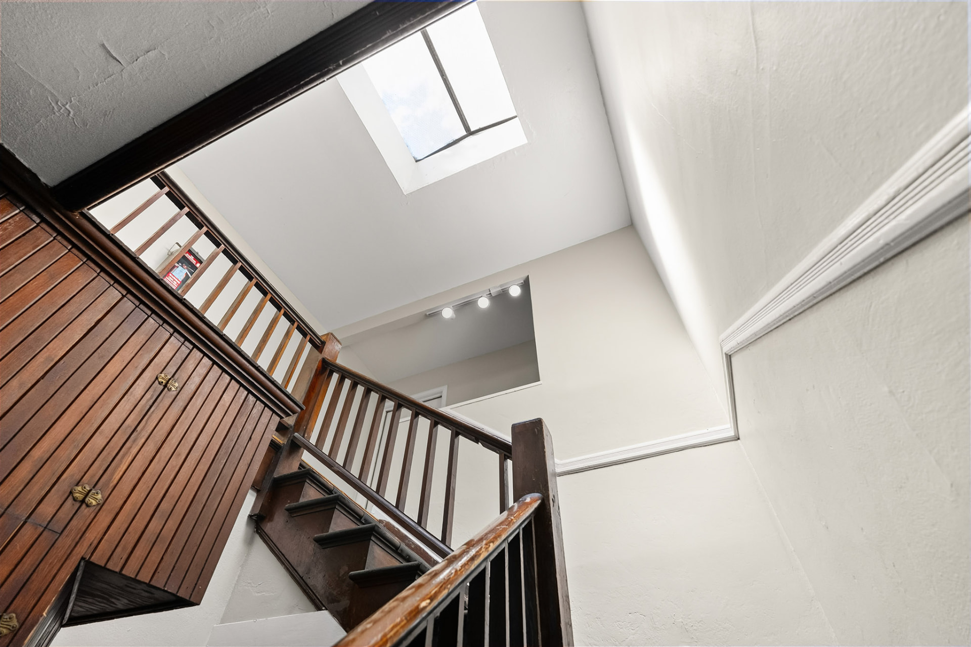Historic wood stairway and skylit landing serving the upper-floor units