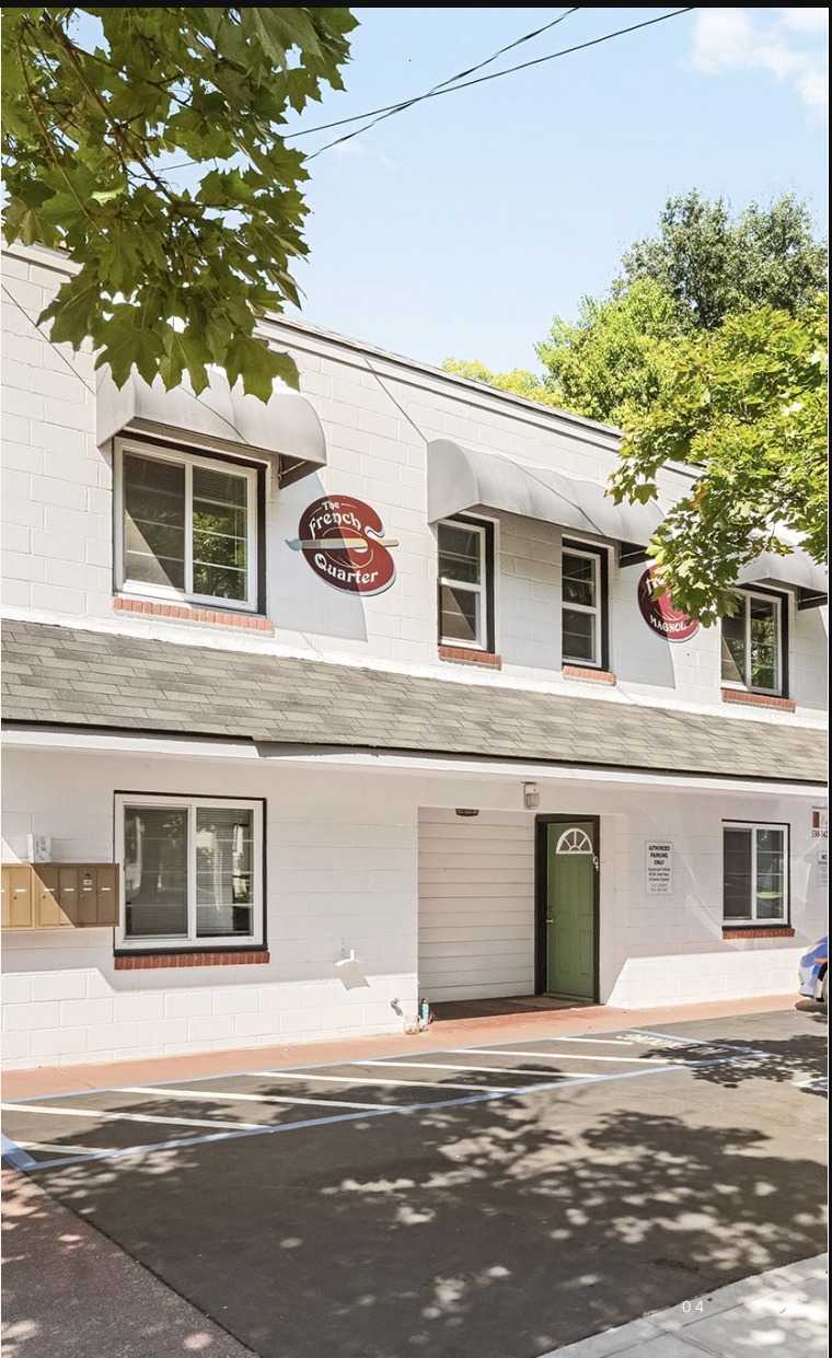 The French Quarter building at 1121 Magnolia Avenue with striped awnings and parking field