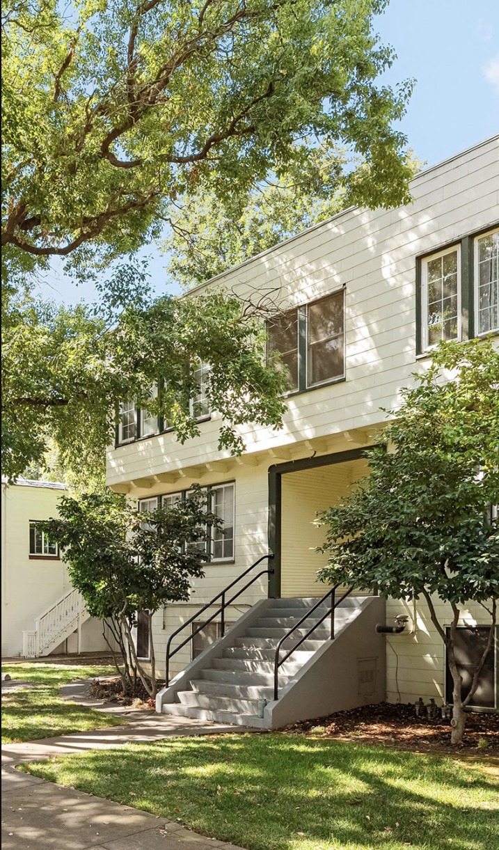 Front elevation and entry stairway of the Magnolia Apartments beneath mature shade trees
