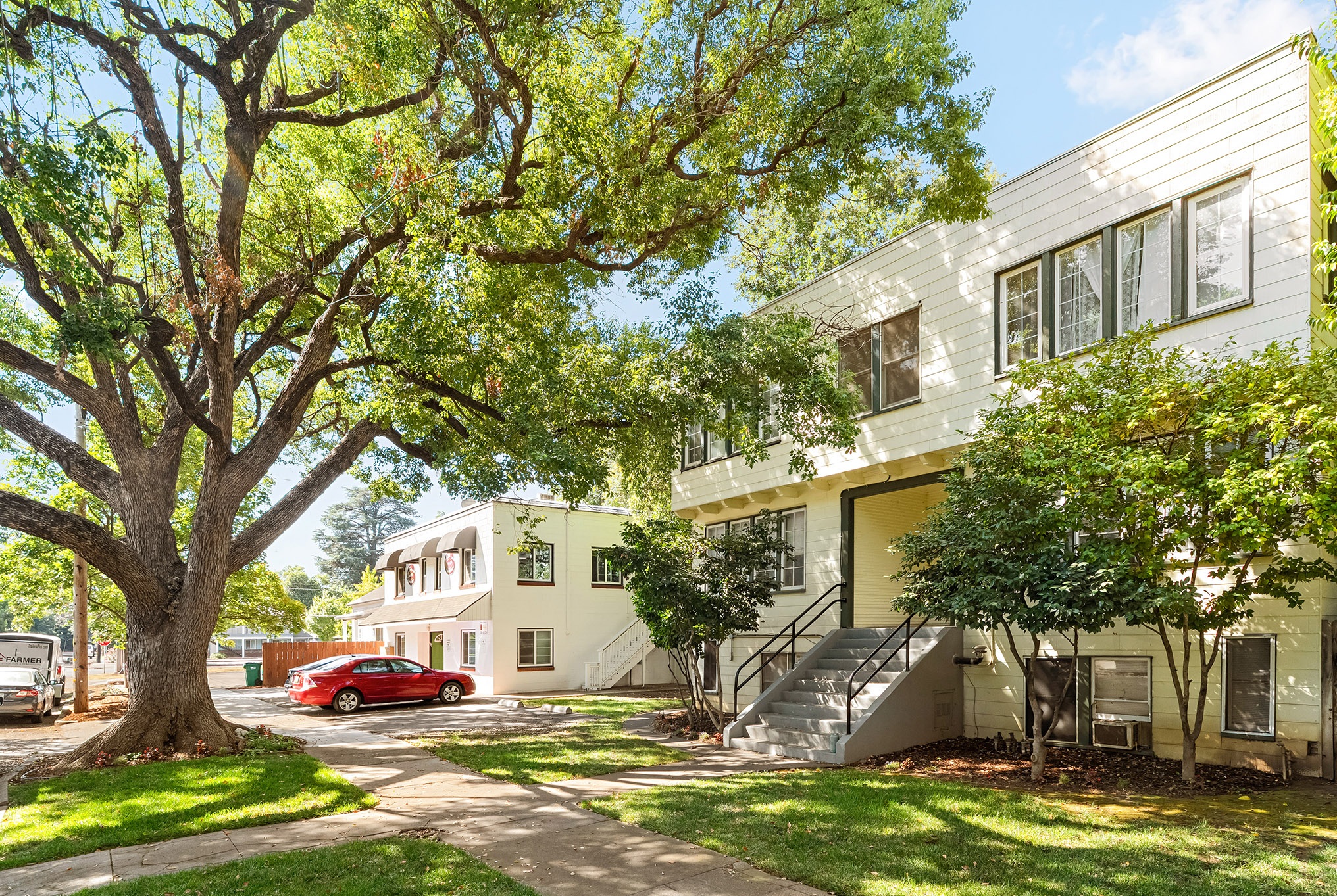 Side elevation of the Magnolia Apartments buildings beneath a mature oak canopy
